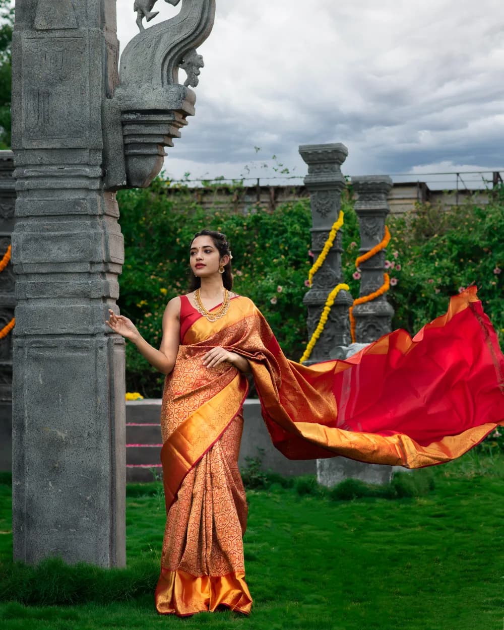 Woman in a maroon silk saree with gold zari in a heritage setting